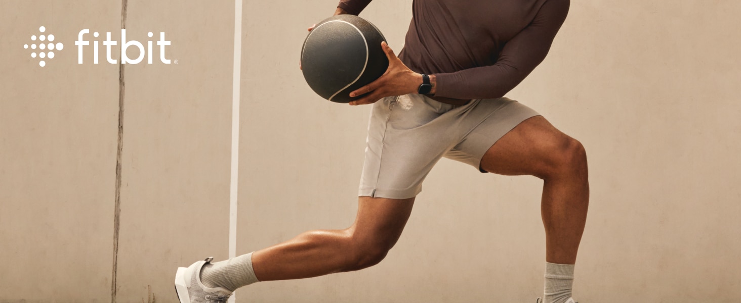 Man working out with medicine ball wearing the Fitbit Versa 4